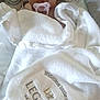 Nala is registered to the contest to win money with this photo: baby, pacifier, towel, white_towel, text, embroidery, infant, healthcare, blanket, cute, child, person, portrait, indoors, soft_texture, wrapped, resting, newborn, comfort, gaze