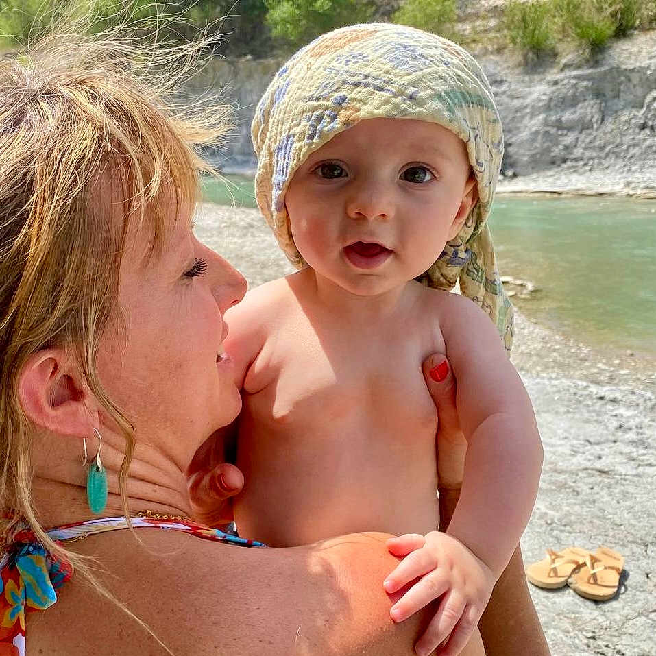 Liam a rejoint le concours — aidez-le/la à gagner de superbes lots ! baby, child, earring, family, hair, hand, headscarf, holding, nature, outdoor, portrait, river, rock, sandals, skin, summer, sunlight, trees, water, woman