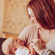 Colton joined the competition — help win amazing prizes! baby, woman, pacifier, holding, smiling, face, head, knitted_sweater, person, indoor, love, mother, child, portrait, closeup, warm_lighting, skin, hand, affection, cozy