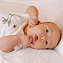 Colton is registered to the contest to win money with this photo: baby, infant, newborn, lying_down, blanket, soft_texture, white, clothing, onesie, cute, face, hand, skin, portrait, child, young, sleepy, peaceful, indoors, closeup