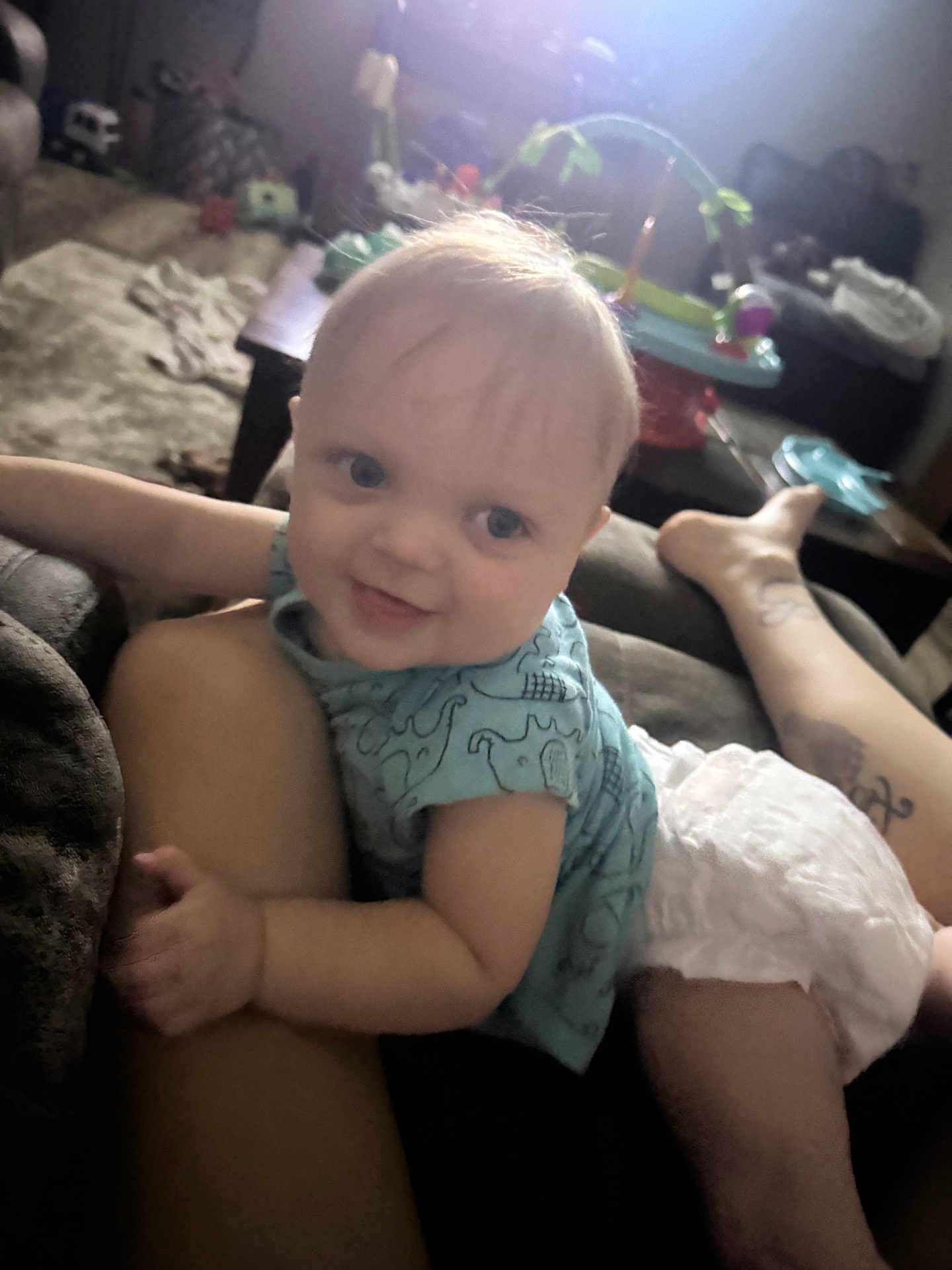 Greyson joined the competition — help win amazing prizes! baby, child, smile, happy, infant, blue_shirt, diaper, leg, tattoo, living_room, couch, furniture, toy, table, carpet, person, home_interior, relaxation, indoor, cute