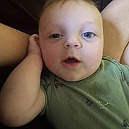 Greyson is registered to the contest to win money with this photo: baby, infant, child, face, blue_eyes, green_shirt, palm_tree_print, hand, curious_expression, close_up, portrait, skin, person, cute, young, indoors, lying_down, soft_lighting, background, casual_clothing