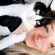 Pickles joined the competition — help win amazing prizes! cat, woman, selfie, indoor, smile, blonde_hair, black_and_white_cat, face, pet, cuddle, happy, cozy, casual_clothing, home, sitting, close_up, portrait, feline, human, relaxation