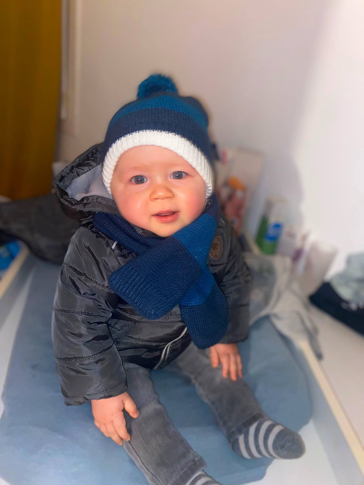 Awen Anddy a rejoint le concours — aidez-le/la à gagner de superbes lots ! baby, baby_toddler_clothing, beanie, cap, child, comfort, electric_blue, fashion_accessory, flooring, fun, headwear, jacket, knit_cap, person, personal_protective_equipment, room, sitting, sleeve, smile, toddler