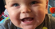 Montgomery joined the competition — help win amazing prizes! baby, infant, child, smiling, happy, portrait, face, close_up, indoor, seated, activity_center, baby_toy, colorful, gray_clothing, yellow_toy, floral_background, home, laughter, looking_at_camera, playtime