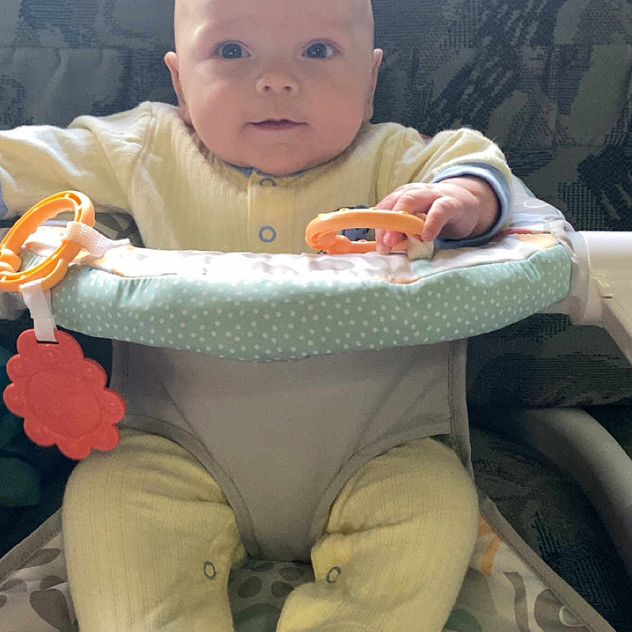 Montgomery joined the competition — help win amazing prizes! baby, baby_seat, child, closeup, colorful_toy, curious_expression, face, feet, hands, human, indoor, infant, natural_light, patterned_cushion, playtime, seated, soft_fabric, toy, yellow_pajamas, young_child