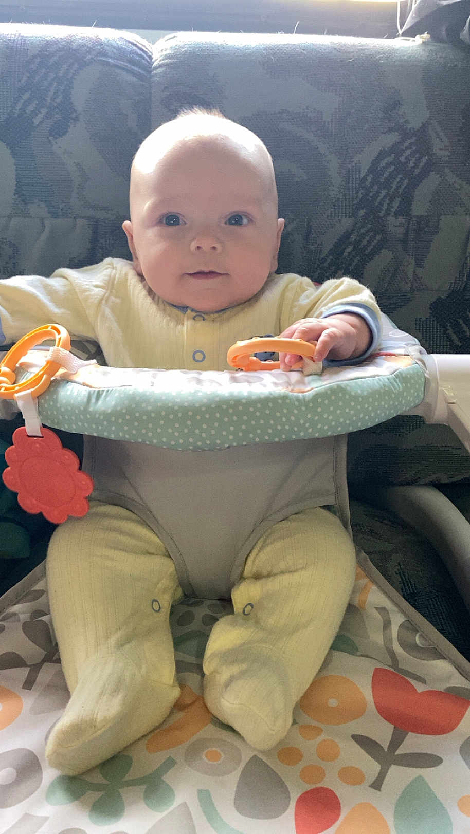 Montgomery joined the competition — help win amazing prizes! baby, child, infant, yellow_pajamas, toy, baby_seat, colorful_toy, face, hands, feet, patterned_cushion, indoor, curious_expression, natural_light, seated, soft_fabric, closeup, human, young_child, playtime