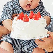 Nathan joined the competition — help win amazing prizes! baby, child, birthday, cake, strawberries, dessert, sitting, highchair, portrait, indoors, smiling, sleepy, open_mouth, striped_clothing, bare_feet, adult_hands, celebration, white_background, food, family