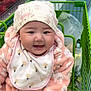 baby, child, shopping_cart, grocery_store, produce, red_peppers, green_peppers, bib, hat, pink_onesie, smiling, face, cute, indoor, person, clothing, food, shopping, happy, infant