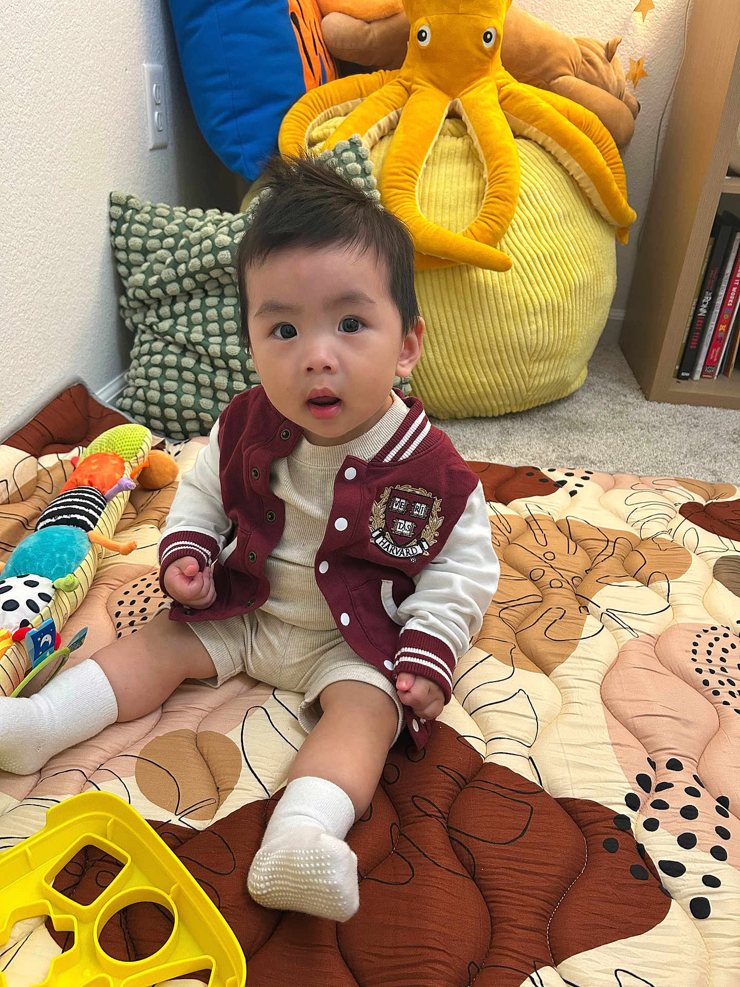 Eugene Vang joined the competition — help win amazing prizes! toddler, child, baby, toy, plush, octopus, quilt, colorful, socks, sitting, indoor, carpet, pillow, cushion, sleeveless, jacket, curious, face, person, room
