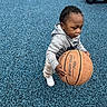toddler, basketball, playground, blue_surface, child, hoodie, plaid_pants, white_shoes, outdoor, sport, toy, small_child, determined, daylight, active, person, recreation, casual_clothing, young_child, play
