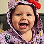 baby, child, smiling, hoodie, purple_clothing, red_bow, halloween_theme, pumpkin_pattern, crib, hand, face, teeth, indoor, happy, cute, person, apparel, infant, portrait, expression