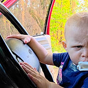 Scarlett joined the competition — help win amazing prizes! toddler, child, baby, pacifier, steering_wheel, car_interior, hand, face, expression, serious, blue_shirt, seat, window, door, outdoor, nature, trees, daylight, person, vehicle
