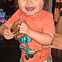 child, toddler, smiling, indoor, person, hands, shorts, shirt, patterned_clothing, blue_socks, happy, face, hair, skin, holding, standing, cute, bright_eyes, colorful, joyful