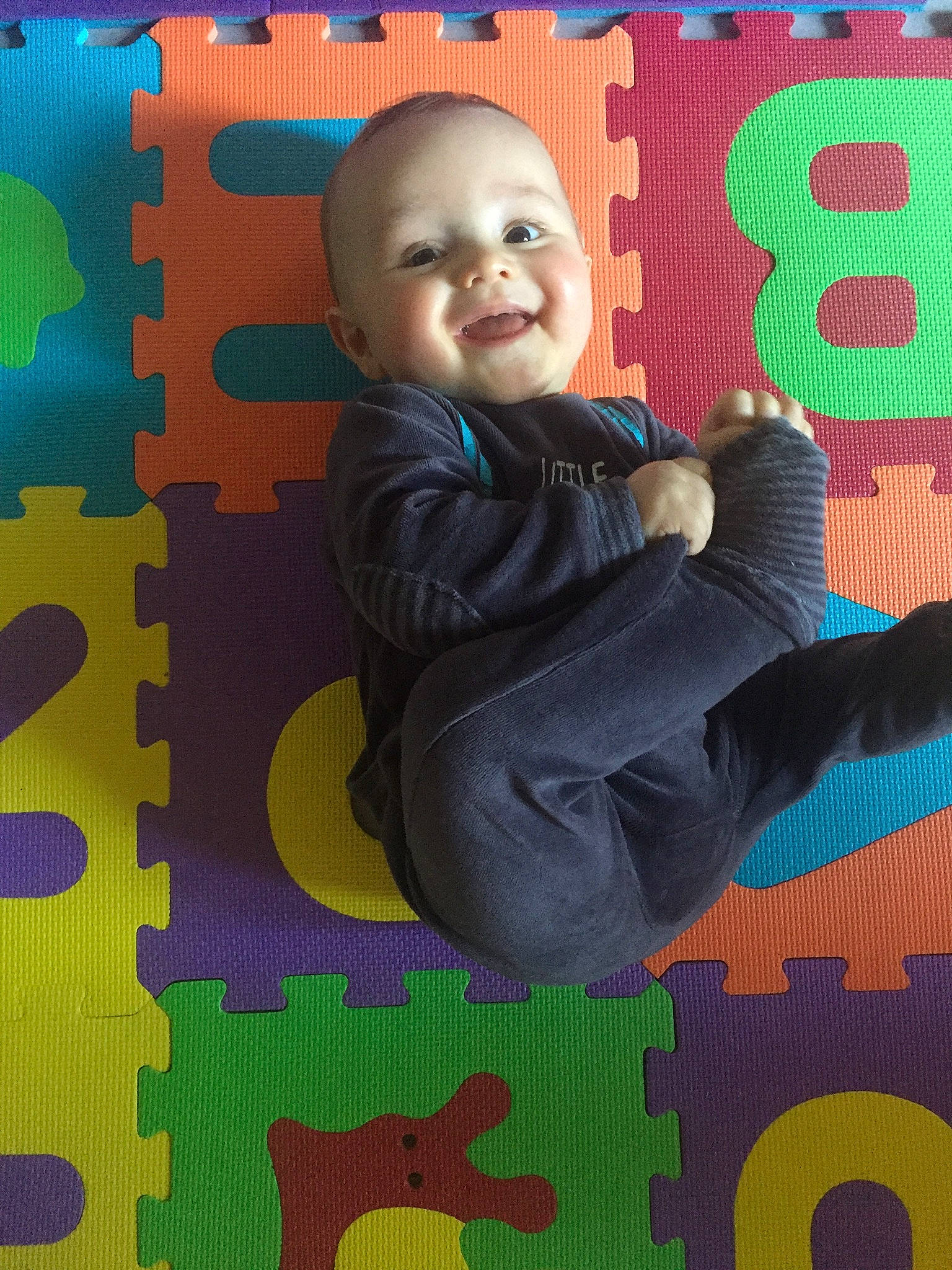 Louïs a rejoint le concours — aidez-le/la à gagner de superbes lots ! art, baby, baby_laughing, baby_toddler_clothing, child, comfort, design, flooring, font, fun, green, happy, orange, pattern, person, photograph, playground, smile, snapshot, textile