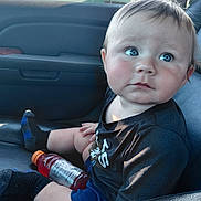 Isaac is registered to the contest to win money with this photo: baby, child, infant, portrait, sitting, car, car_interior, car_seat, blue_eyes, serious_expression, face, eyes, short_hair, black_shirt, shorts, sock, bottle, sports_drink, sunlight, indoor