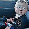 baby, child, infant, portrait, sitting, car, car_interior, car_seat, blue_eyes, serious_expression, face, eyes, short_hair, black_shirt, shorts, sock, bottle, sports_drink, sunlight, indoor