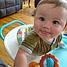 baby, child, infant, portrait, face, tongue_out, curious, indoors, living_room, walker, baby_walker, toy, rattle, mirror, colorful, wood_floor, furniture, chair, smiling, close_up