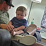 Isaac is registered to the contest to win money with this photo: child, toddler, adult, man, sitting, lap, indoor, portrait, family, chair, recliner, sneaker, shoe, barefoot, lamp, curtain, bottle, home, casual, serious_expression