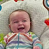 baby, blanket, cheerful, child, colorful, cute, face, happy, indoors, infant, knitted_blanket, lying_down, onesie, play_gym, portrait, smiling, soft_texture, striped_clothing, toy, young_child