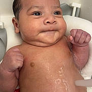 Auriel is registered to the contest to win money with this photo: baby, infant, wet_hair, mohawk, bath, water, fists, chubby_cheeks, skin, face, seat, expression, cute, child, newborn, indoors, portrait, head, torso, relaxing