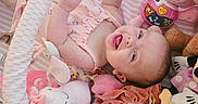 Olivia joined the competition — help win amazing prizes! baby, infant, smile, pink_clothing, stuffed_toy, doll, playpen, toy, happy, child, face, soft_toy, lying_down, cushion, fabric, cute, indoor, infancy, playtime, childhood
