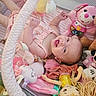 baby, infant, smile, pink_clothing, stuffed_toy, doll, playpen, toy, happy, child, face, soft_toy, lying_down, cushion, fabric, cute, indoor, infancy, playtime, childhood