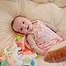 Olivia is registered to the contest to win money with this photo: baby, bright_eyes, child, closeup, colorful, comfortable, cozy, cute, fabric_tags, happy, indoors, infant, lying_down, pink_dress, playful, plush_toy, portrait, small_child, smiling, soft_cushion