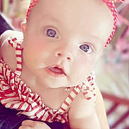Olivia is registered to the contest to win money with this photo: baby, background, blue_eyes, child, closeup, clothing, cute, expression, face, hand, headband, indoors, infant, person, polka_dot, portrait, skin, soft_lighting, striped_clothing, young