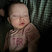 Meadow is registered to the contest to win money with this photo: baby, child, closeup, cute, eyelashes, fabric, face, floral_pattern, head, indoor, infant, onesie, patterned_background, peaceful, pink_clothing, portrait, resting, sleeping, soft_lighting, young_child