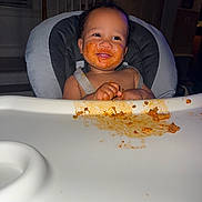 Julien joined the competition — help win amazing prizes! baby, high_chair, food, messy, spaghetti_sauce, face, hands, meal, happy, smiling, indoor, child, feeding, tongue_out, clothing, seat, person, cute, dining, kitchen