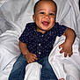 Julien is registered to the contest to win money with this photo: baby, child, smiling, face, denim_jeans, navy_shirt, polka_dot, barefoot, bracelet, white_blanket, happy, cute, portrait, infant, sitting, indoors, human, skin, head, arm