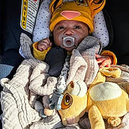 Julien is registered to the contest to win money with this photo: baby, pacifier, car_seat, blanket, plush_toy, hat, yellow, infant, child, cute, warm, soft, cozy, clothing, face, hand, indoors, seat, comfort, sleepy