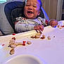 baby, bread, child, clothing, cute, feeding, food, happy, high_chair, indoor, laughing, long_sleeve, messy, person, seat, smile, strawberry, toddler, tray, young