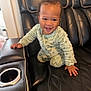 Julien is registered to the contest to win money with this photo: baby, child, smiling, crawling, onesie, black_couch, leather, cup_holder, indoor, happy, cute, infant, young_child, furniture, hand, face, head, seated, home, cozy