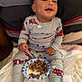 Julien is registered to the contest to win money with this photo: baby, child, pajamas, food, plate, bed, smile, happy, sitting, footwear, pillow, blanket, indoor, clothing, person, face, hand, meal, cute, infant