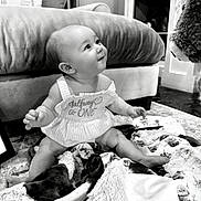 Lainey is registered to the contest to win money with this photo: baby, black_and_white, blanket, child, clothing, couch, cute, decor, furniture, happy, home, indoors, infant, playful, plush_toy, portrait, sign, sitting, smile, young
