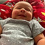 baby, smiling, infant, blanket, red_blanket, gray_onesie, polka_dot, indoor, child, face, arm, happy, cute, cozy, lying_down, newborn, soft, pattern, comfort, peaceful