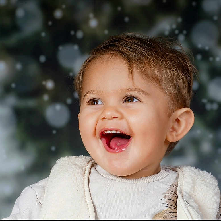 Manhoé participe au concours pour gagner de l'argent avec cette photo : blurred_background, child, clothing, cozy, cute, expression, eyes, face, happy, head, holiday, indoor, joyful, mouth, portrait, smiling, snow, toddler, vest, winter