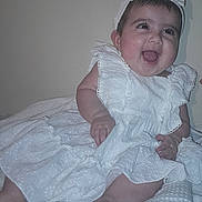 Marwa Khaliq joined the competition — help win amazing prizes! baby, child, infant, smile, happy, dress, headband, white_clothing, blanket, sitting, cute, indoors, portrait, joy, fingers, feet, young_child, skin, person, face