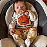 baby, infant, child, portrait, sitting, bouncer, pacifier, pumpkin, halloween, costume, clothing, white_outfit, orange, smiling_pumpkin, indoor, cozy, chair, blanket, facial_expression, photography