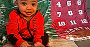 Kai is registered to the contest to win money with this photo: baby, child, red_jacket, water_bottle, milestone_blanket, numbers, couch, indoor, smiling, sitting, curious, cozy, colorful, fabric, soft, person, portrait, young_child, happy, clothing