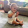 baby, carpet, chewing, child, clothing, couch, curly_hair, cute, floor, indoor, light, living_room, person, shorts, sitting, striped, toddler, toy, window, young