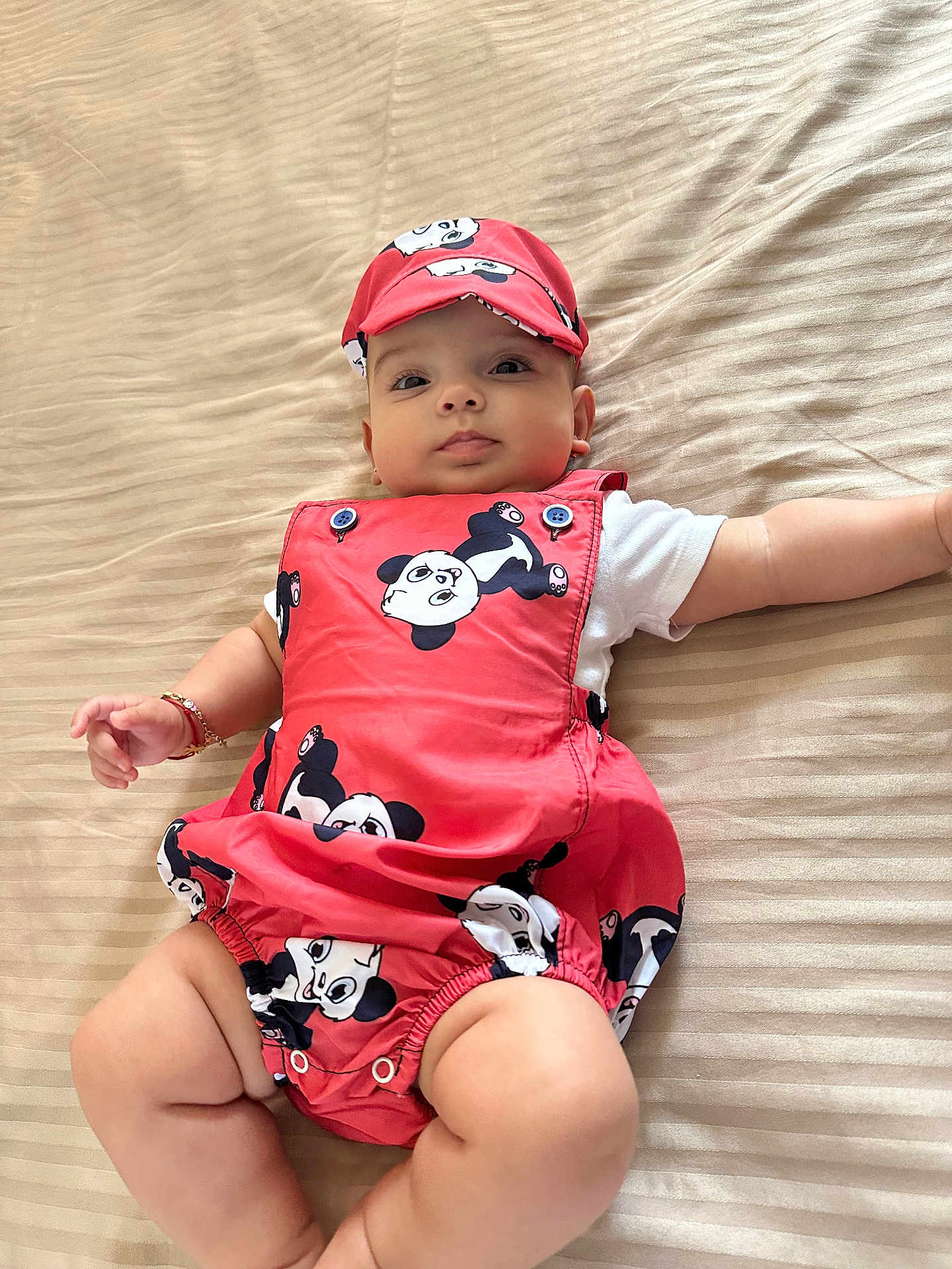 Leea participe au concours pour gagner de l'argent avec cette photo : baby, infant, panda_print, cap, red_outfit, bedspread, striped_bed, lying_down, cute, child, adorable, skin, arm, leg, clothing, face, headwear, bracelet, indoors, portrait