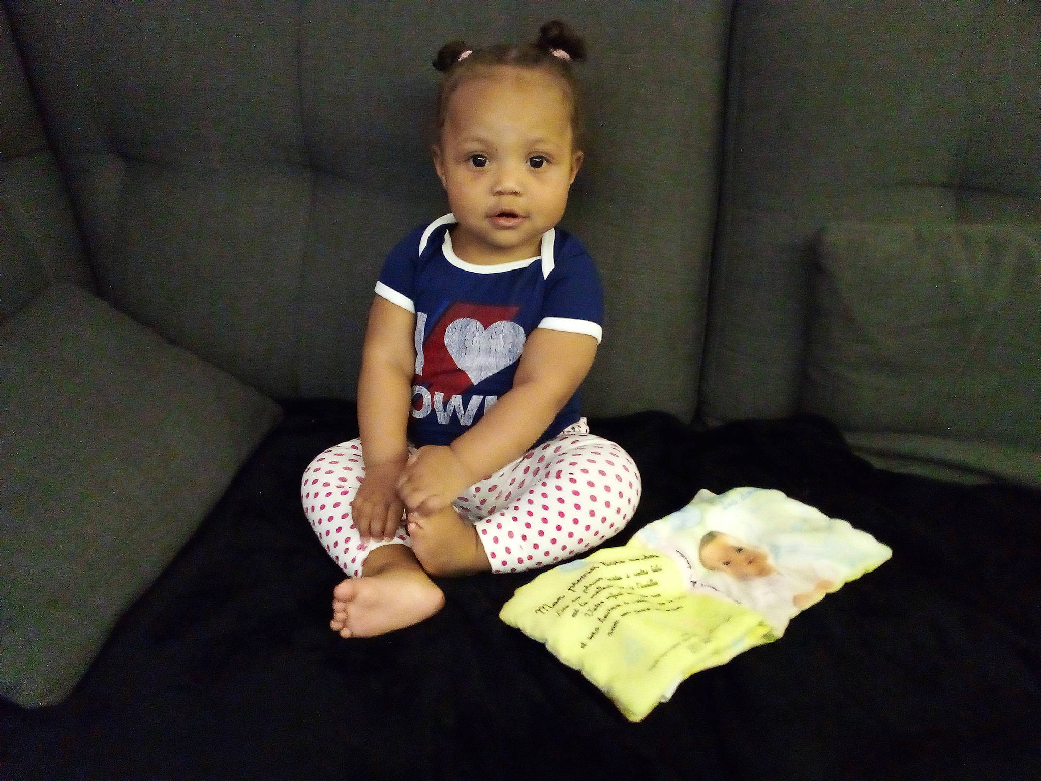 Aliyah participe au concours pour gagner de l'argent avec cette photo : arm, baby, baby_toddler_clothing, child, comfort, couch, flooring, fun, happy, human_leg, knee, linens, pattern, person, room, sitting, sleeve, t_shirt, thigh, throw_pillow