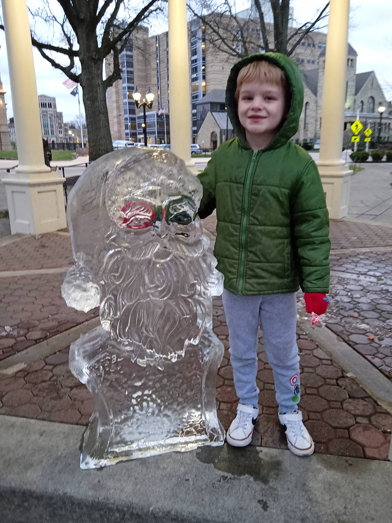 Leon is registered to the contest to win money with this photo: art, asphalt, city, concrete, freezing, fun, joy, leisure, pedestrian, person, road_surface, sculpture, sidewalk, sky, smile, standing, statue, street, temple, toddler