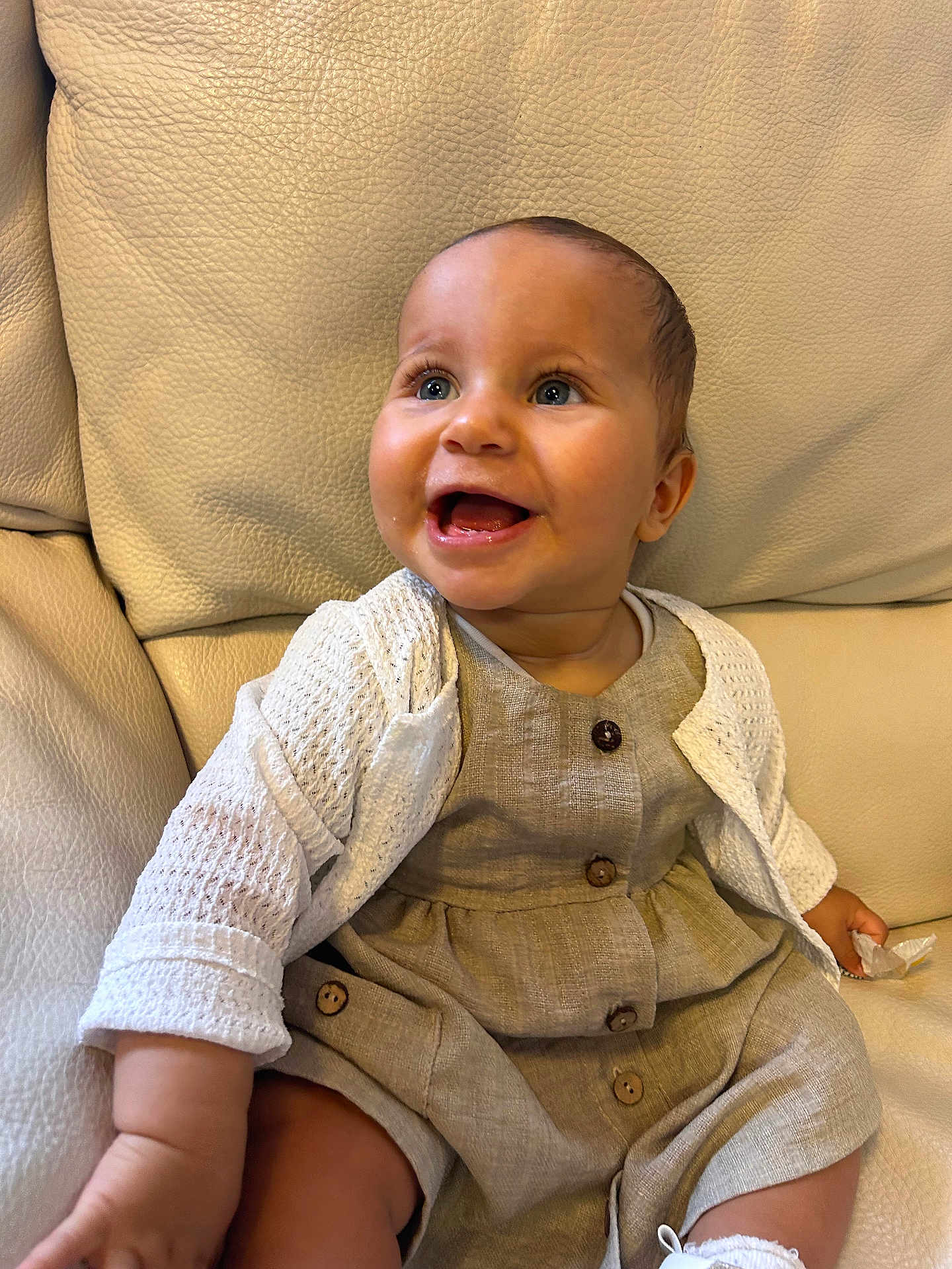 Naya participe au concours pour gagner de l'argent avec cette photo : baby, child, smiling, happy, sitting, couch, leather, clothing, cardigan, buttons, face, portrait, indoor, cute, infant, person, expression, skin, hand, footwear