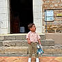 Matis a rejoint le concours — aidez-le/la à gagner de superbes lots ! child, boy, plush_toy, steps, stone, building, door, outdoor, side_view, casual_clothing, white_shoes, pavement, curious_expression, holding_toy, young_child, short_hair, daylight, wall, railing, standing