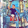 Matis participe au concours pour gagner de l'argent avec cette photo : child, boy, carousel, donkey, ride, amusement_park, smiling, outdoor, daylight, playful, fun, seat, wooden_floor, clothing, shorts, sandals, rope, lights, decorative, happy