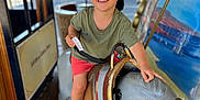 Matis a rejoint le concours — aidez-le/la à gagner de superbes lots ! child, boy, smiling, carousel, donkey, ride, cap, summer_clothing, ticket, amusement_park, outdoor, wooden_floor, playful, happy, portrait, toy, fun, daylight, casual, seat